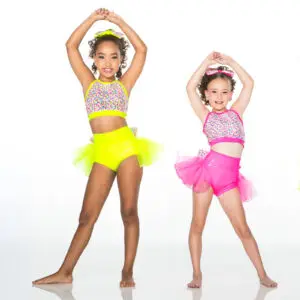 Two young dancers in colorful costumes pose with raised arms.