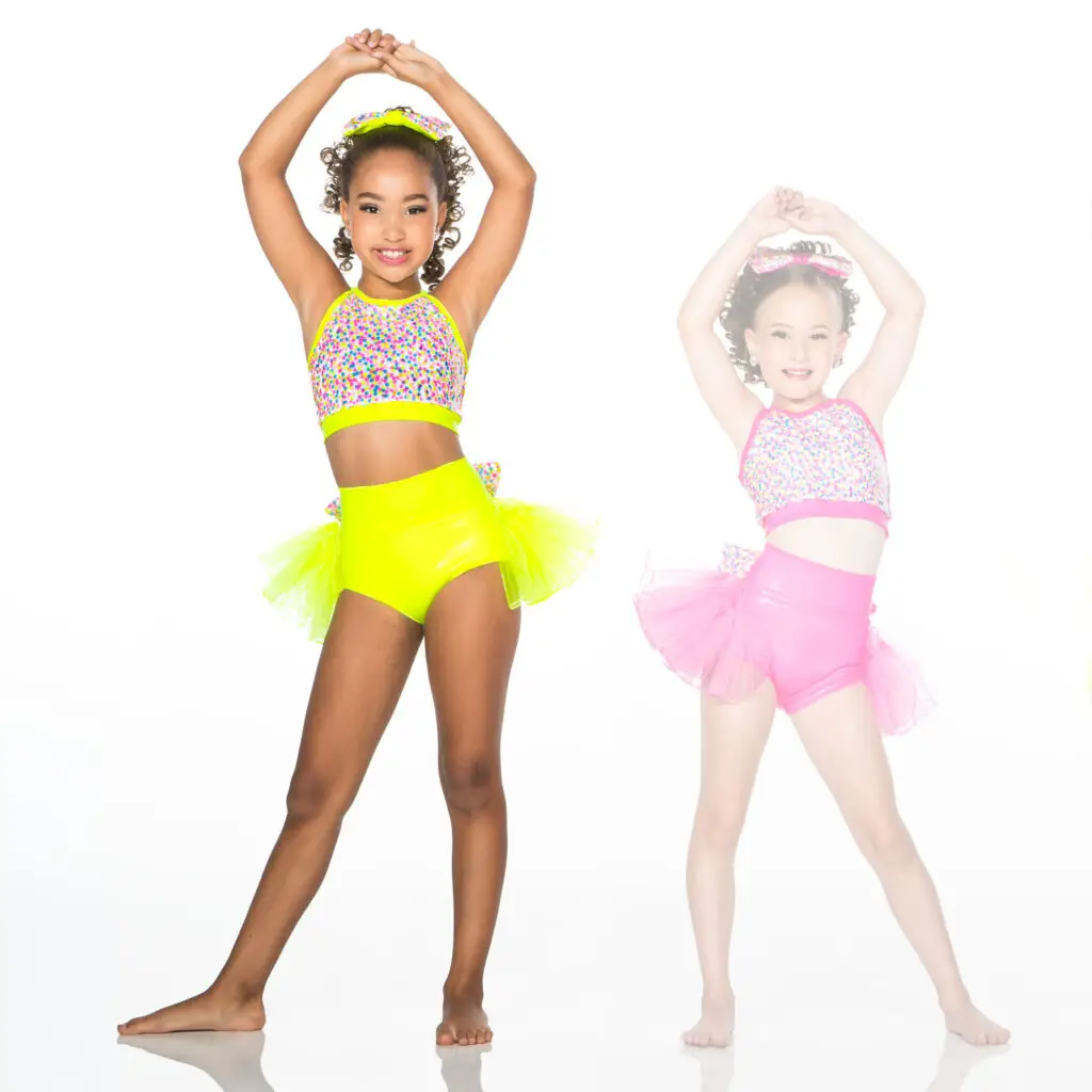 Young dancers wearing colorful neon costumes pose with raised arms.
