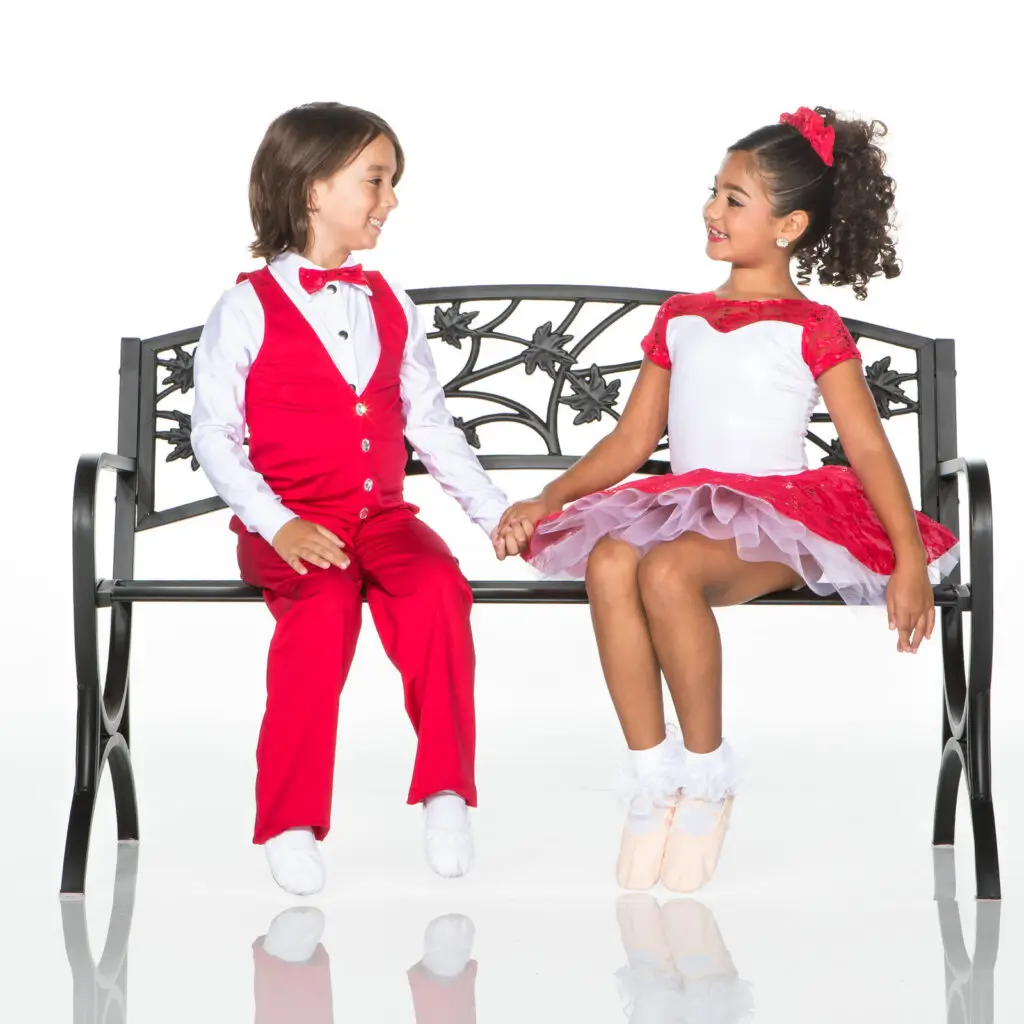 Children in red costumes holding hands on a bench
