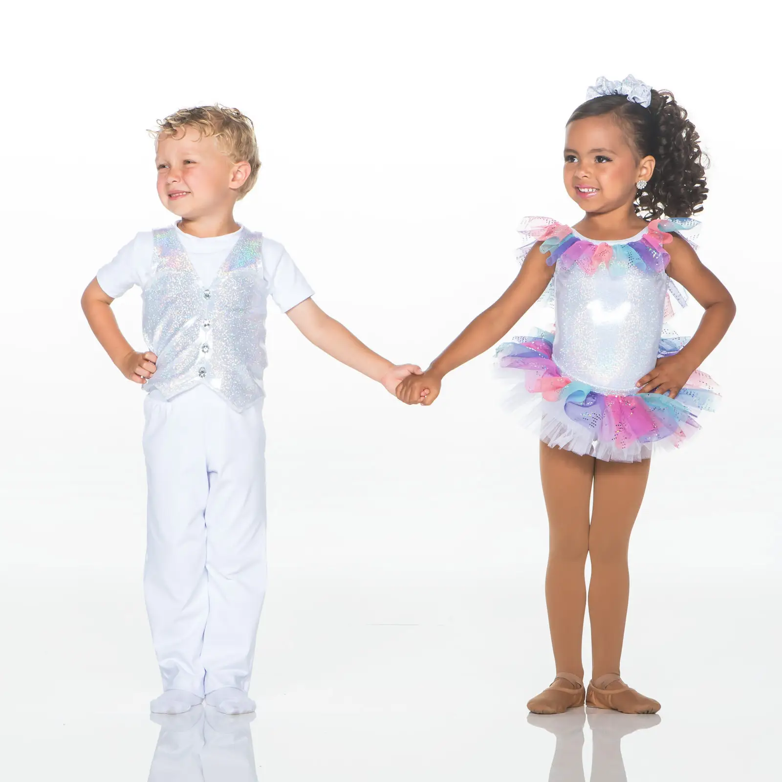 Two children holding hands in colorful dance costumes