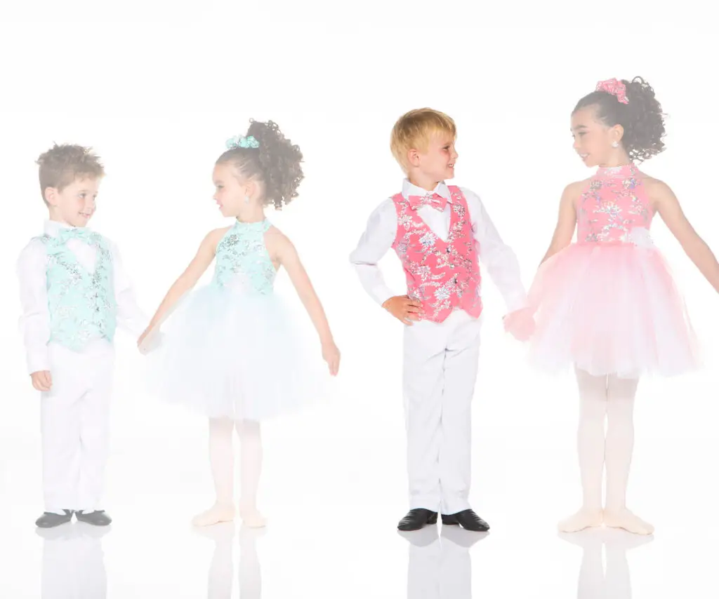 Four children in colorful ballroom dance costumes smiling together