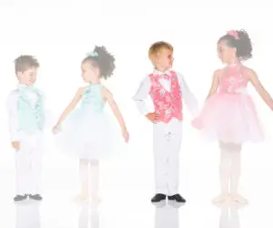 Four children in colorful ballroom dance costumes smiling together