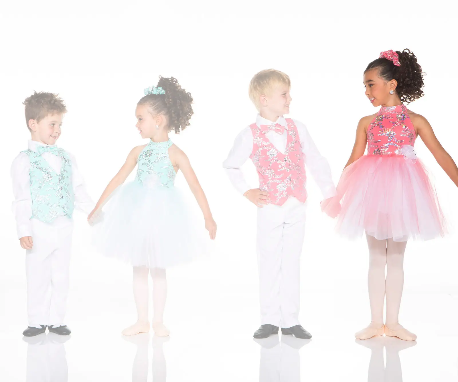 Four children wearing colorful ballroom dance costumes
