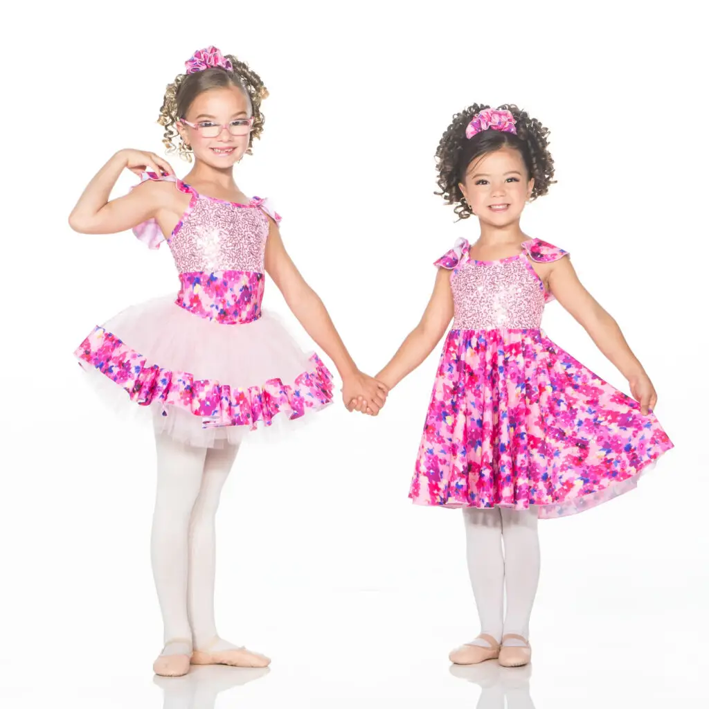 Two young dancers holding hands in pink floral costumes