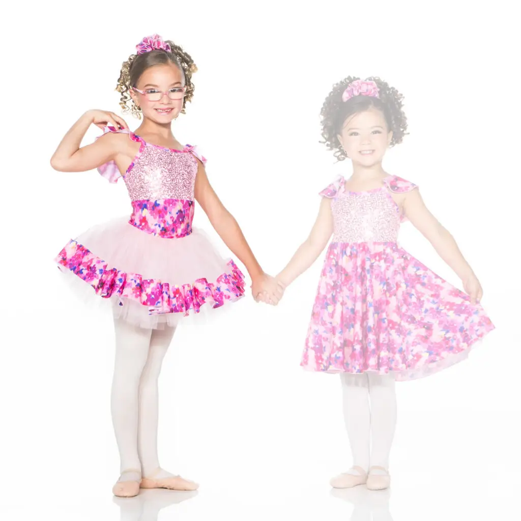 Two young girls in pink floral dance costumes holding hands