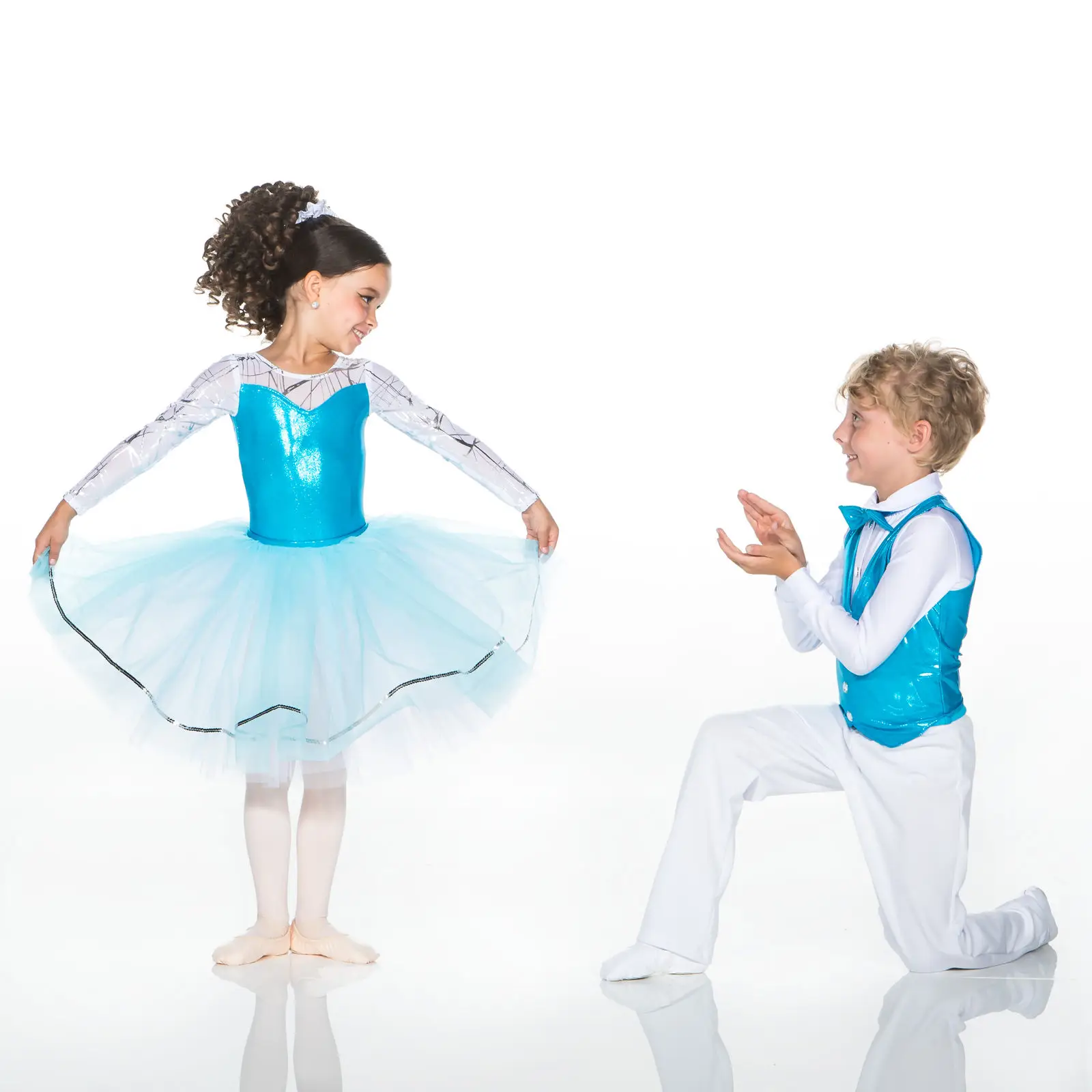 Young dancers in blue costumes, girl twirling as boy applauds