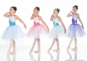 Four young ballerinas in colorful tutus posing against white background.