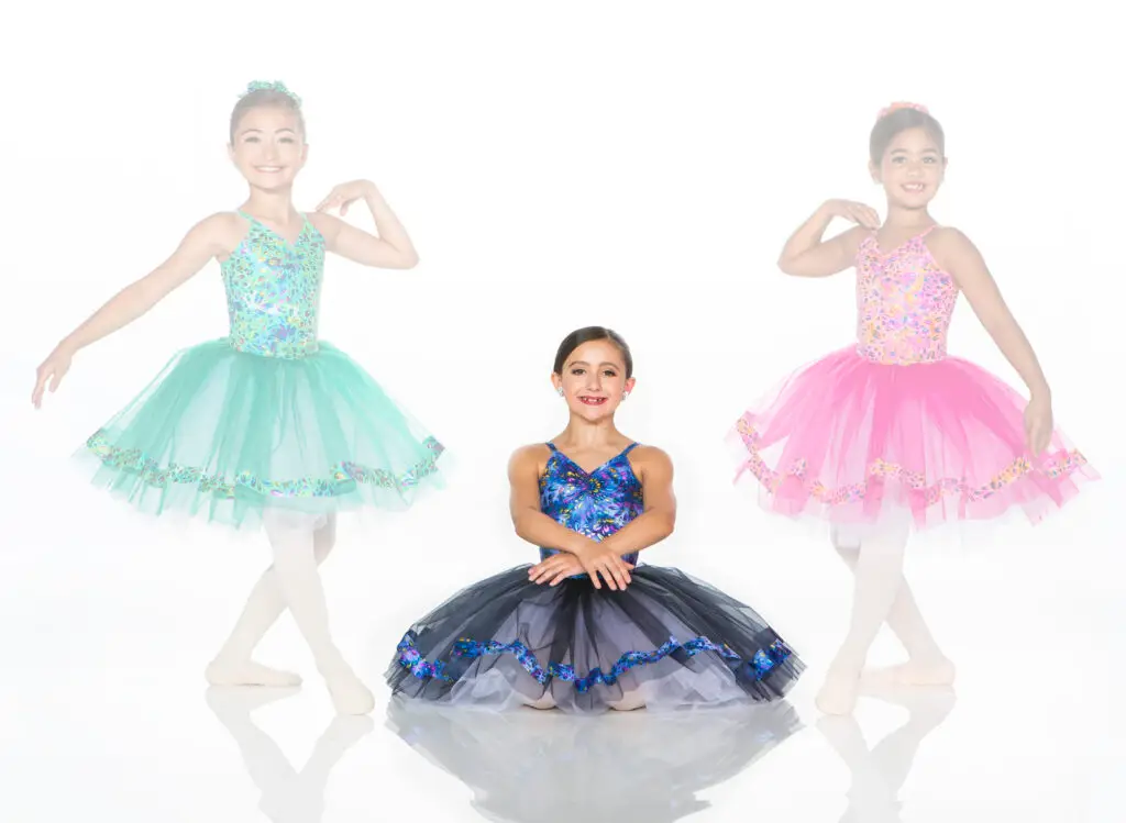 Three young ballerinas wearing colorful tutus against a white background.