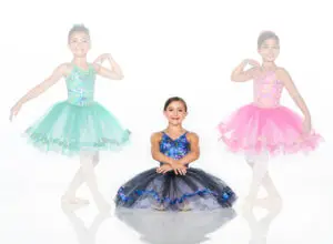 Three young ballerinas wearing colorful tutus against a white background.
