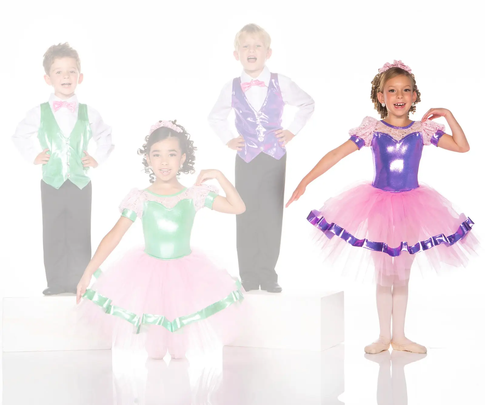 Four children wearing colorful dance costumes and ballet tutus