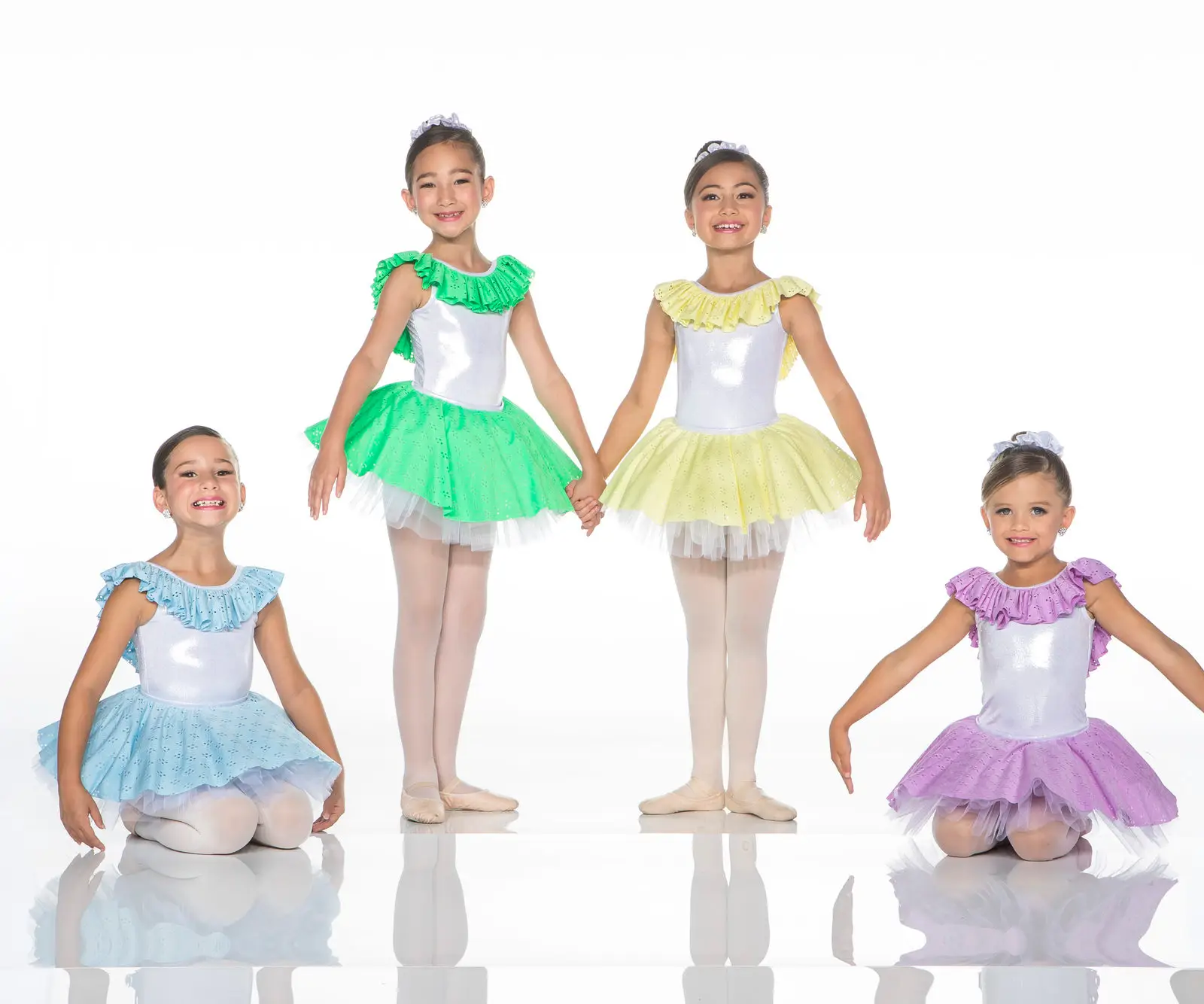 Four young ballerinas wearing colorful tutus pose together.