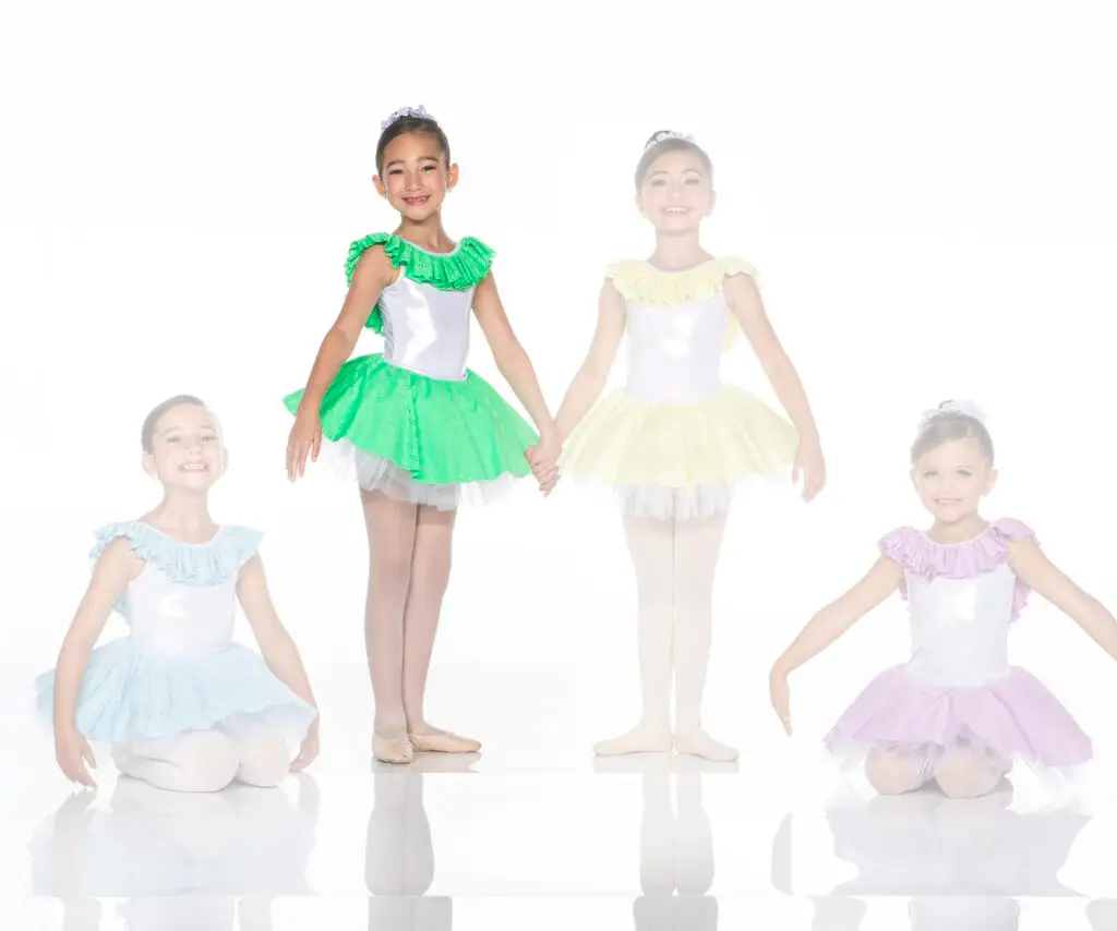 Four young ballet dancers wearing colorful tutus against white background