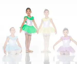 Four young ballet dancers wearing colorful tutus against white background