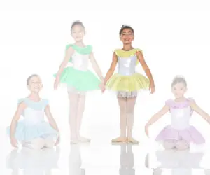 Four young ballerinas wearing pastel ruffled tutus pose together