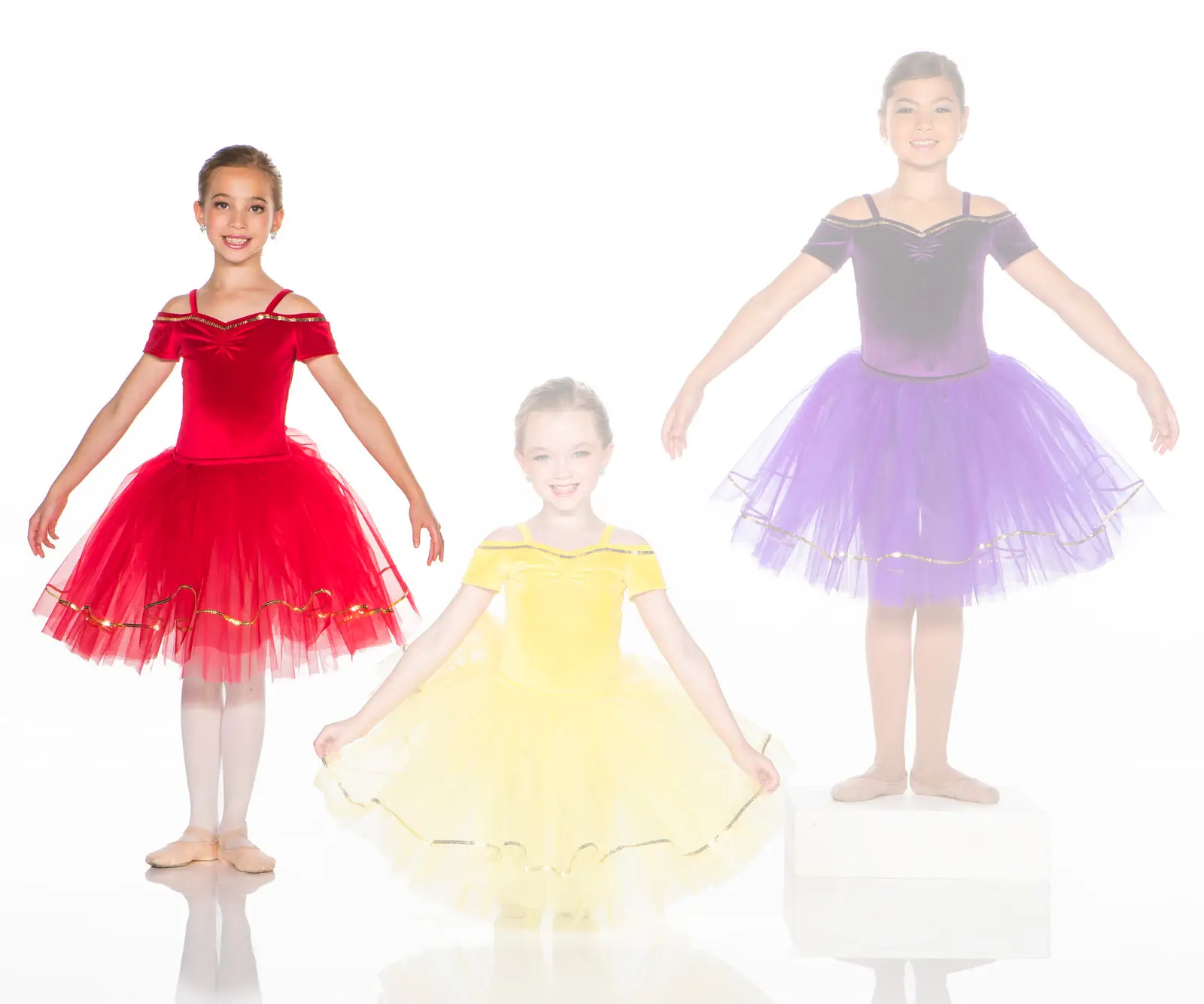Three young ballerinas wearing red, yellow, and purple tutus