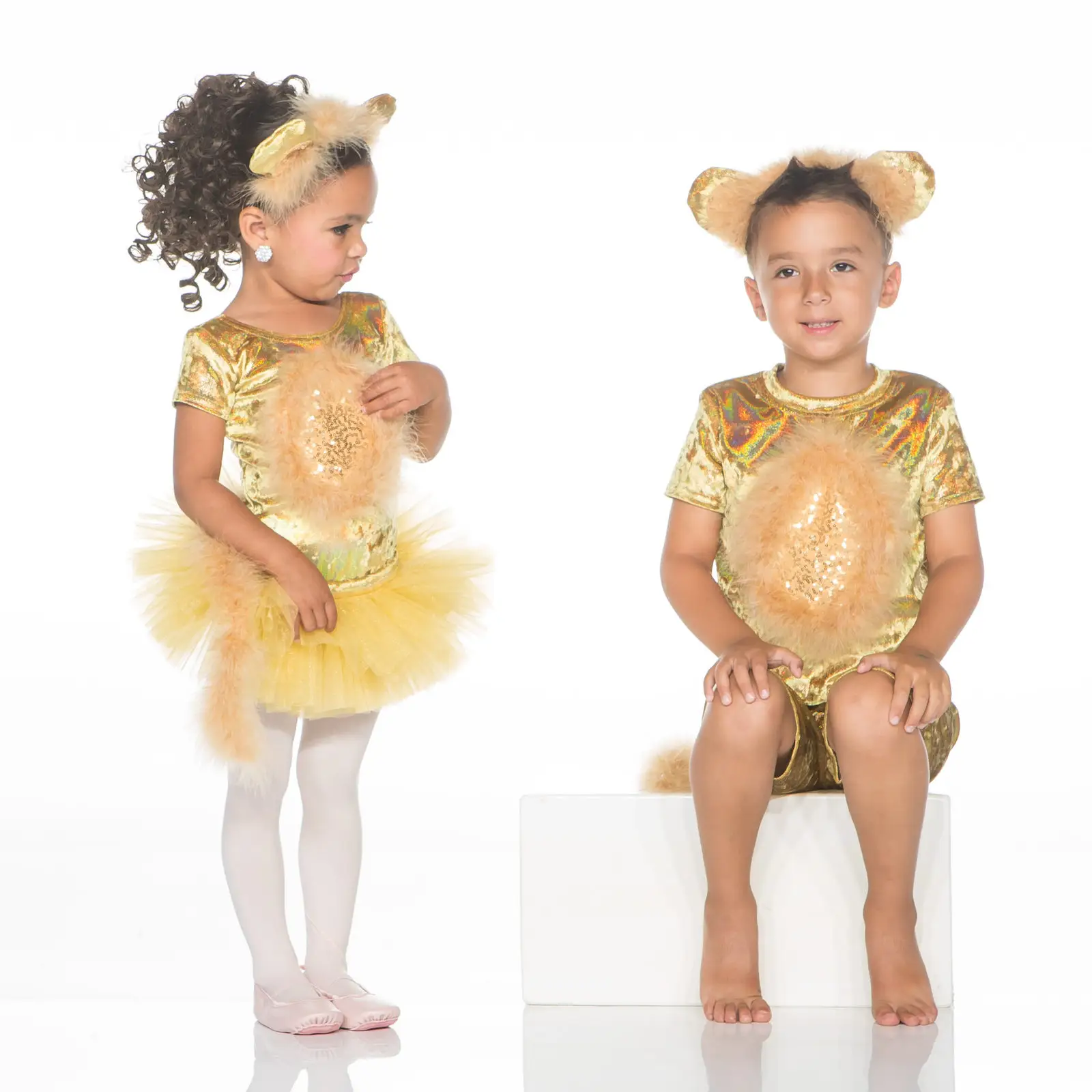 Two children wearing gold bear costumes against white background