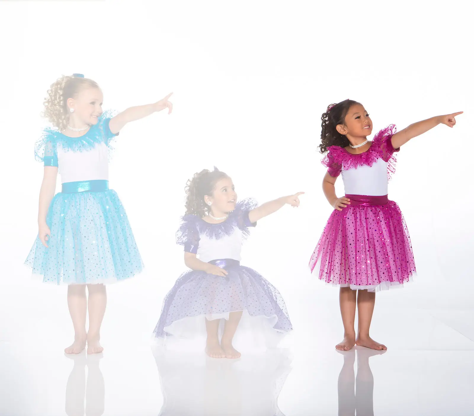 Three girls in colorful dresses pointing right