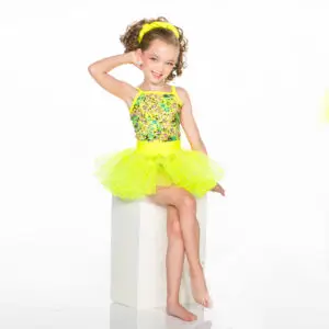 Smiling young dancer in neon yellow tutu seated on pedestal