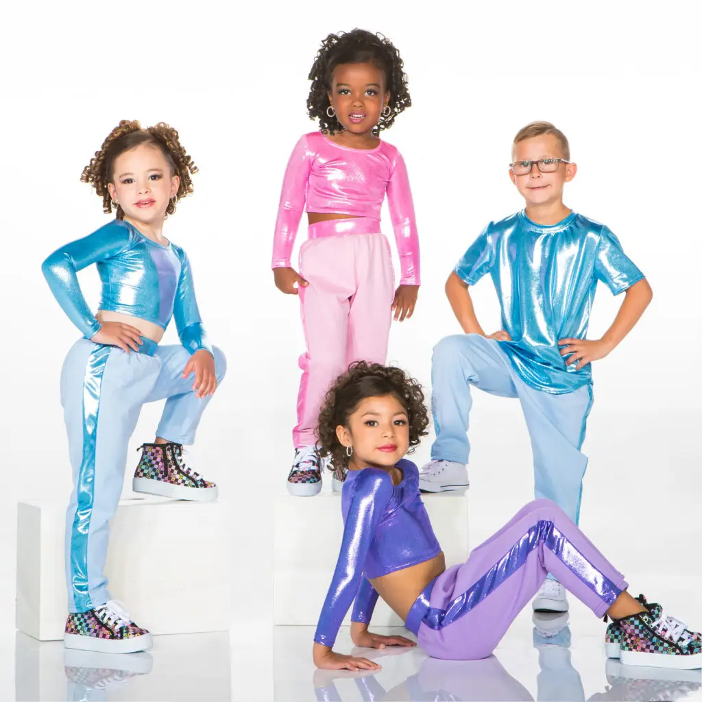 Four children wearing colorful metallic dance outfits pose together.