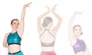 Three dancers modeling colorful sparkly crop tops with raised arms