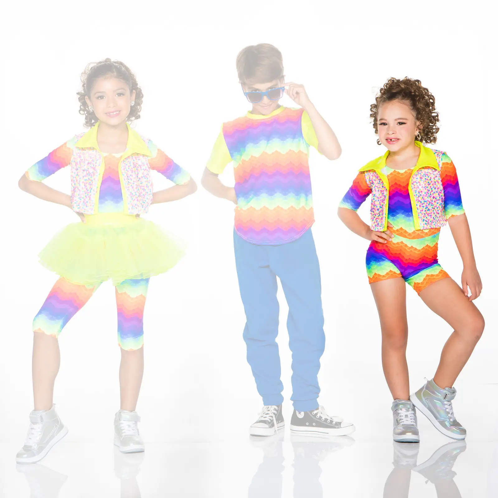 Three children modeling colorful rainbow outfits against white background