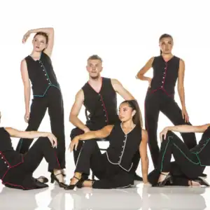 Six dancers pose in black outfits with colorful trim.
