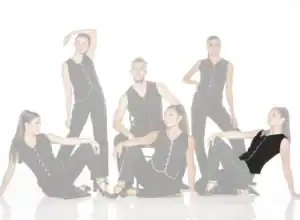 Six dancers pose in black outfits with colorful trim