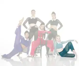 Five dancers pose in colorful sheer costumes around a chair.