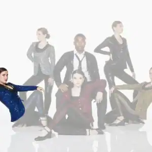 Five performers pose in sparkling jackets against white background.