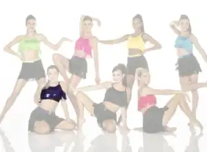 Seven dancers posing in colorful fringe costumes on white background