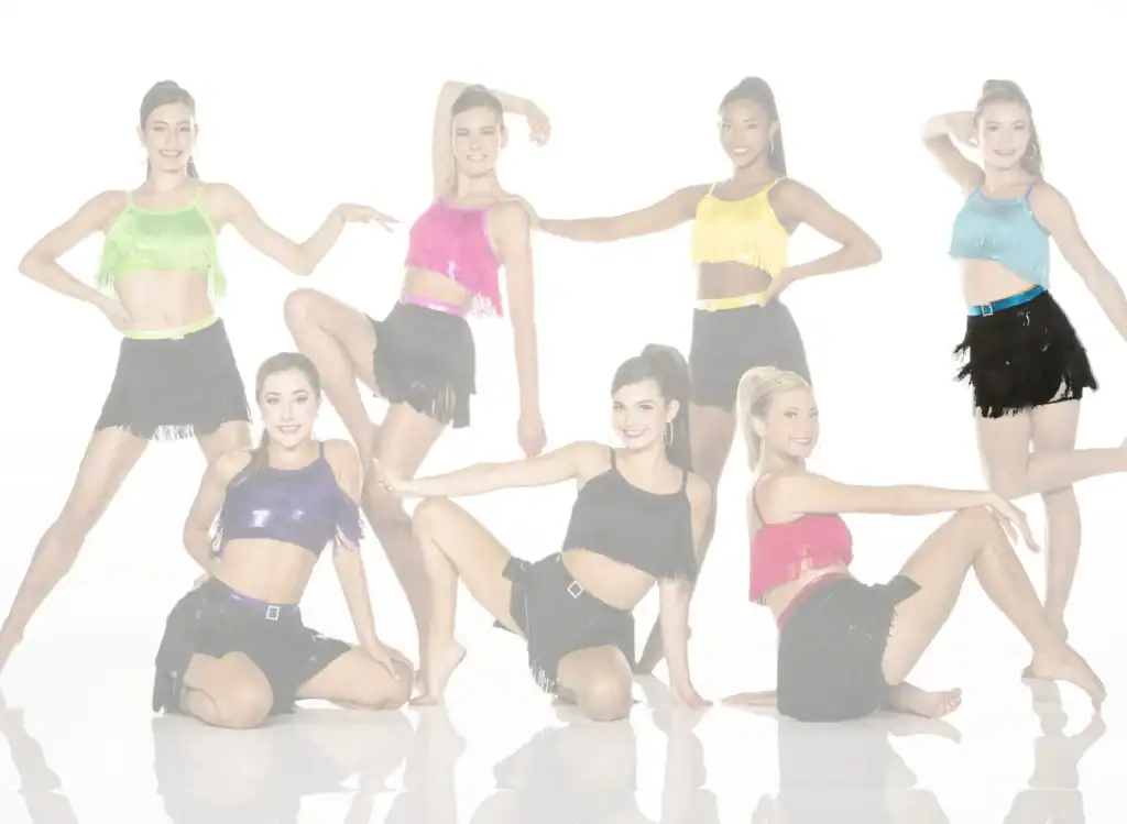 Seven dancers in colorful fringe outfits posing against white background