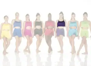 Eight dancers in colorful fringe costumes standing in a row