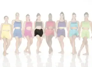 Eight dancers in colorful fringe costumes standing in a row