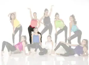 Nine young dancers pose in colorful fringe tops and black leggings.