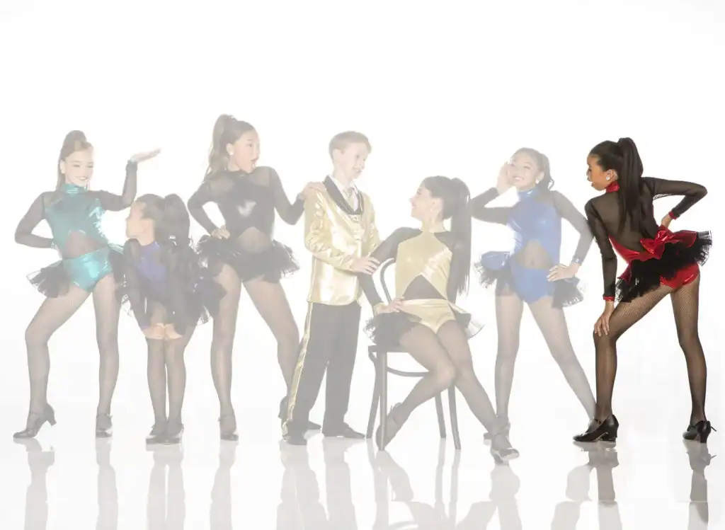 Young dancers in colorful costumes posing on white background