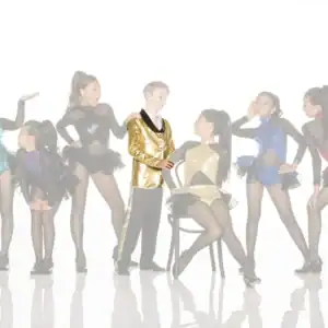 Young dancers pose in colorful costumes around boy in gold jacket