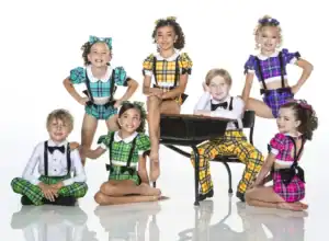 Seven children in colorful plaid dance costumes posing together