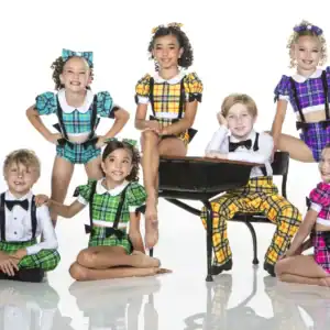Seven children in colorful plaid dance costumes posing together