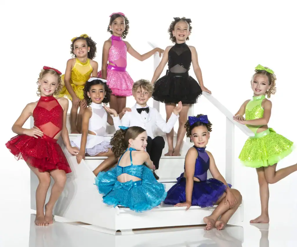 Children in colorful dance costumes posing on white stairs