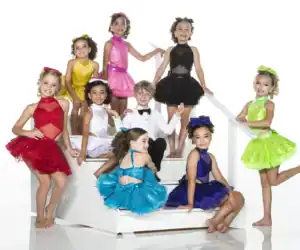 Children in colorful dance costumes posing on white stairs
