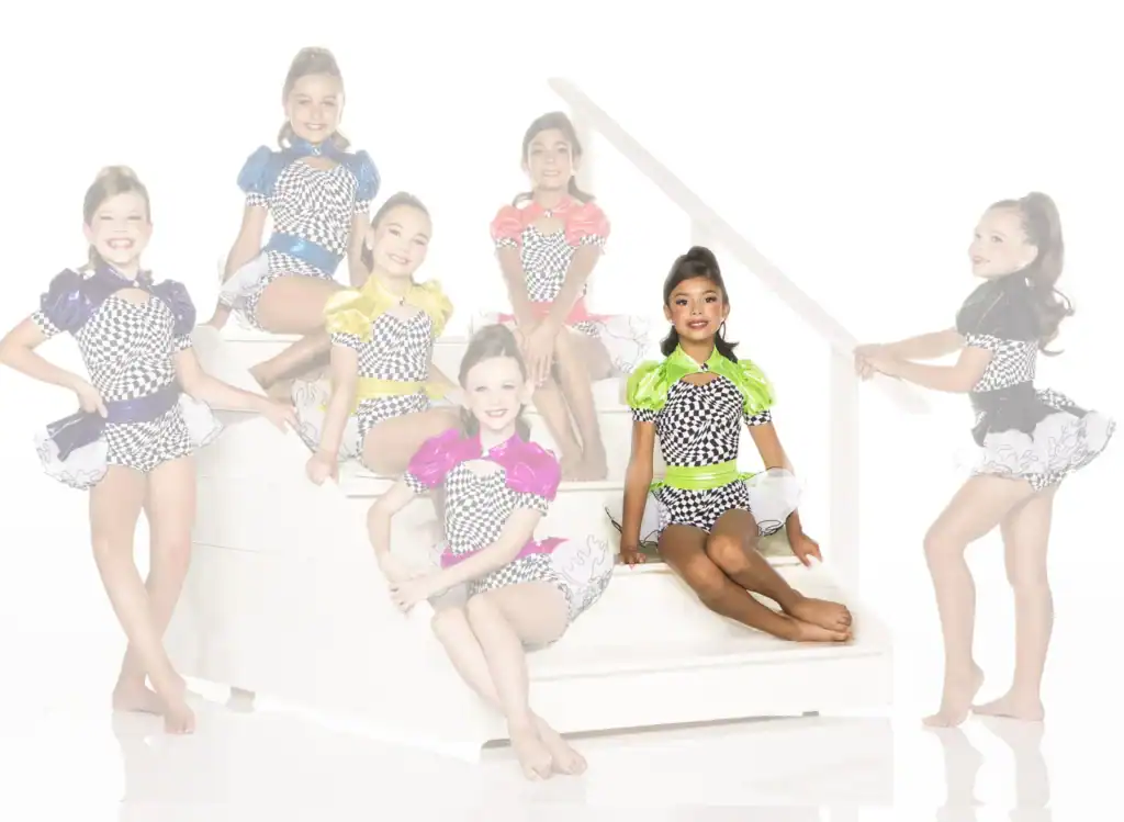 Seven young dancers in colorful checkered costumes on white stairs