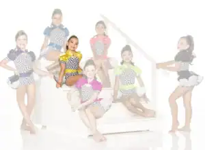 Seven young dancers in colorful checkered costumes pose on stairs.