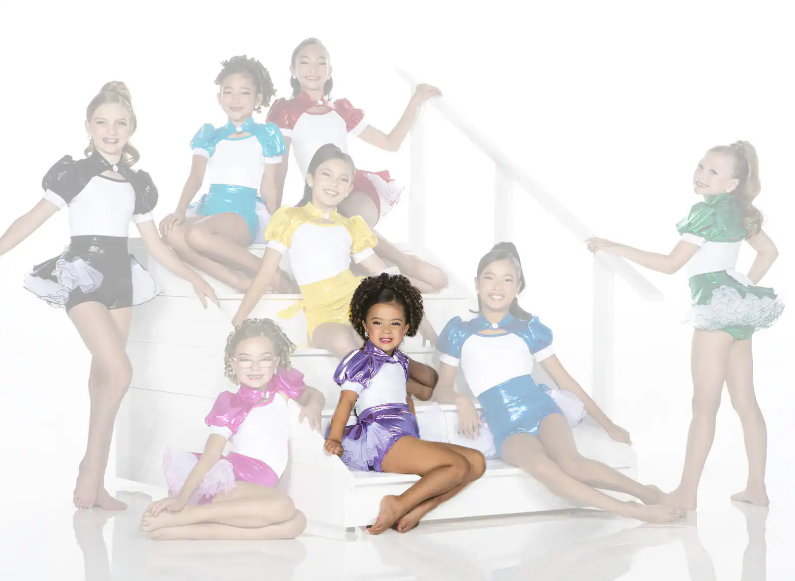 Young dancers in colorful costumes pose on white stairs