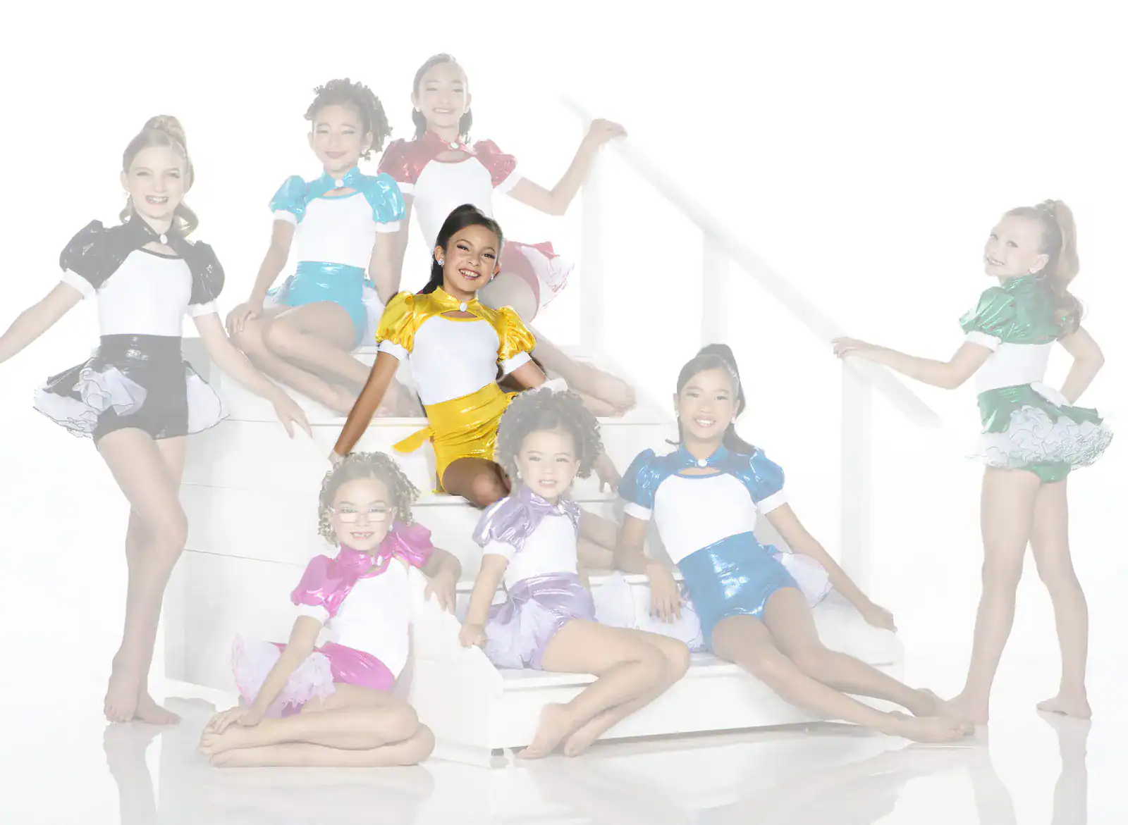 Young dancers pose in colorful costumes on white stairs.