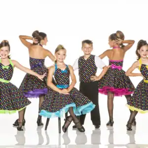 Children in colorful polka-dot dance costumes posing in a studio