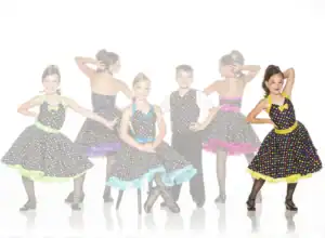 Young girl modeling a black polka-dot dance dress with yellow trim.