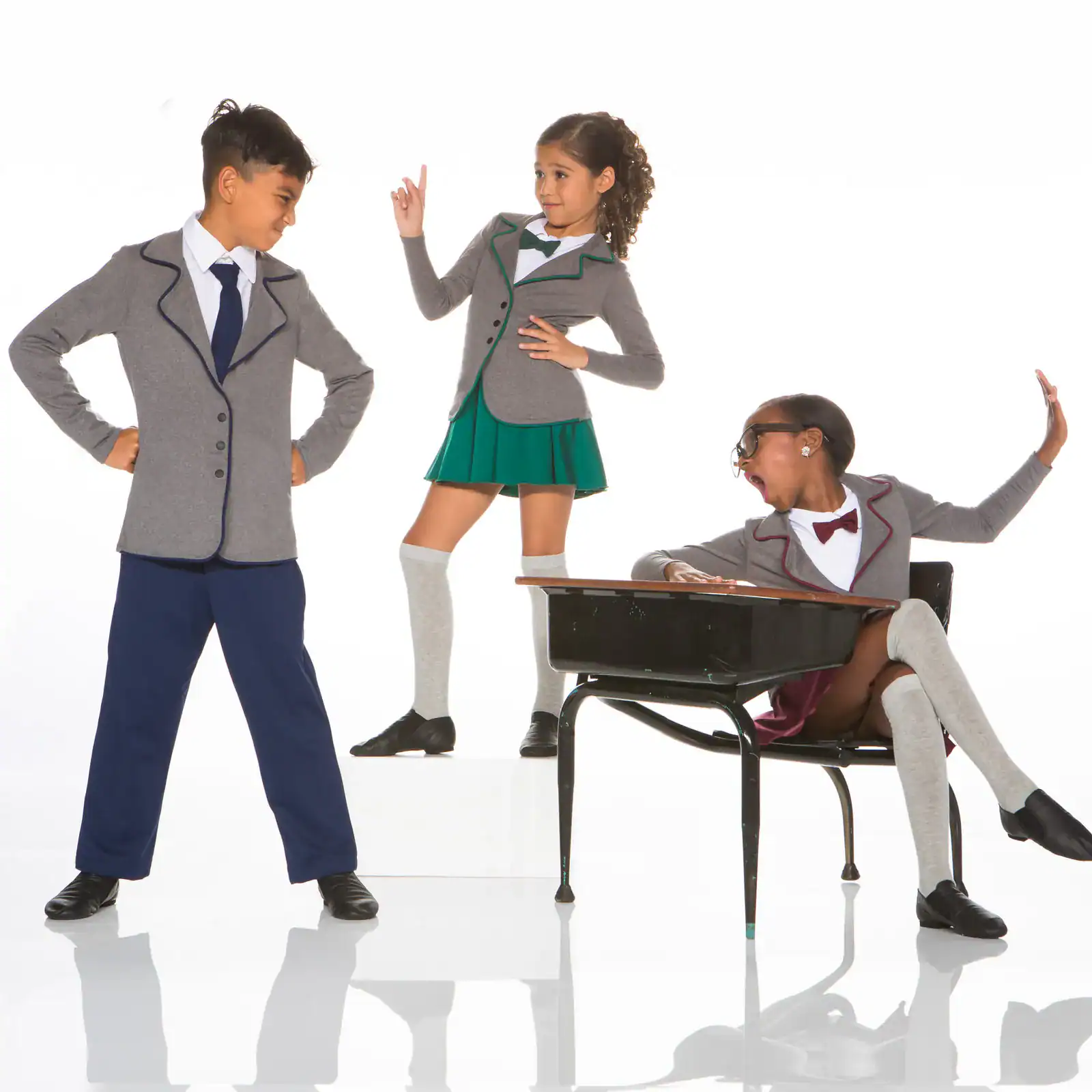 Three children modeling gray school uniforms against white background