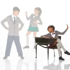 Three schoolchildren in uniforms posing around a desk