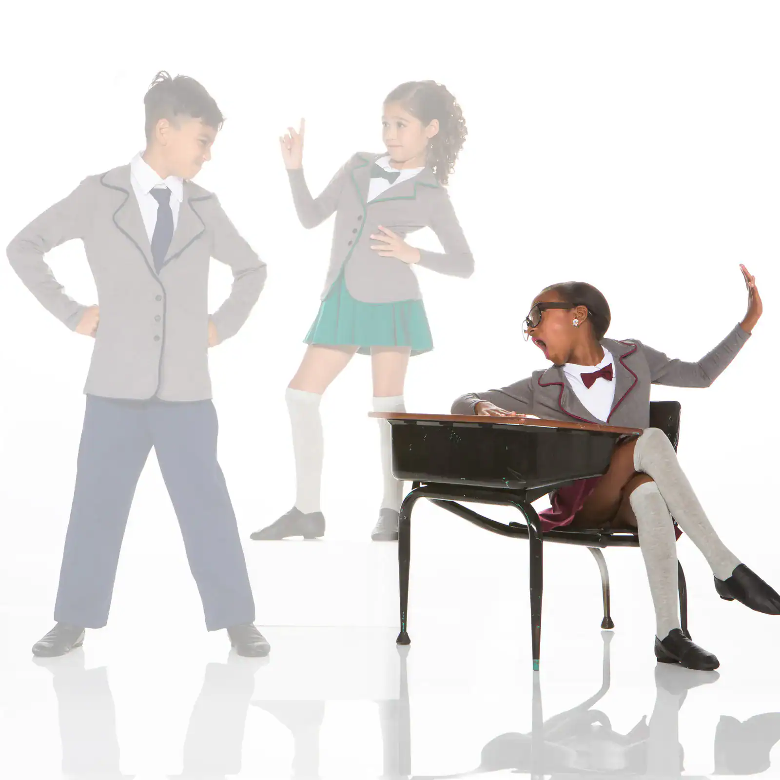 Three schoolchildren in uniforms posing around a desk