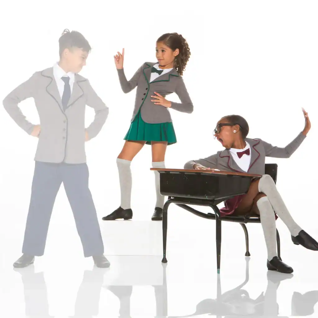 Three children in school uniforms pose around a classroom desk.
